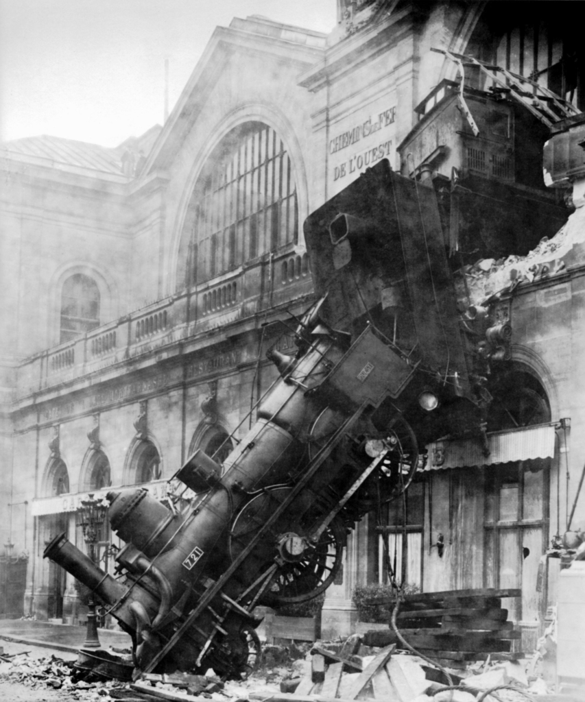 A train bursting out of the back of a train station and falling down onto the street below